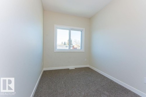 Room featuring a sliding window with white trim, neutral-toned walls, and dark gray carpet flooring - 9814 155 Street, Edmonton, AB - Indoor Photo Showing Other Room