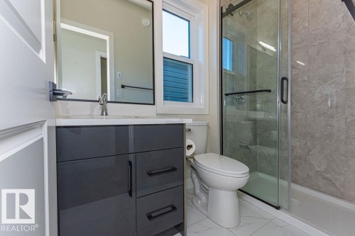 Bathroom featuring a dark gray vanity with a light-toned countertop, a glass-enclosed shower with a black-framed sliding door, and white tiled flooring - 9814 155 Street, Edmonton, AB - Indoor Photo Showing Bathroom