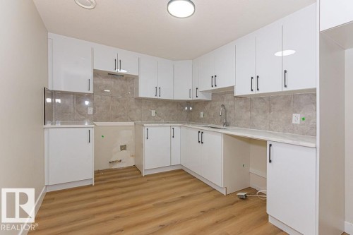 Modern kitchen with white shaker-style cabinetry, a gray tiled backsplash, and light-toned countertops - 9814 155 Street, Edmonton, AB - Indoor Photo Showing Kitchen
