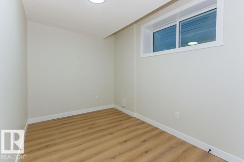 Room featuring wood-finish flooring, light-toned walls, and a white-framed window - 9814 155 Street, Edmonton, AB - Indoor Photo Showing Other Room