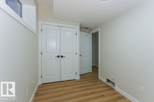 Light wood-finish flooring complements the neutral wall tones - 9814 155 Street, Edmonton, AB - Indoor Photo Showing Other Room