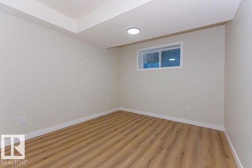 Neutral-toned room featuring light wood-finish flooring and a white trim baseboard - 9814 155 Street, Edmonton, AB - Indoor Photo Showing Other Room