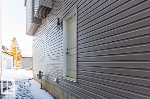 Side exterior featuring horizontal siding, a white entry door, and an exterior wall light fixture - 9814 155 Street, Edmonton, AB - Outdoor With Exterior