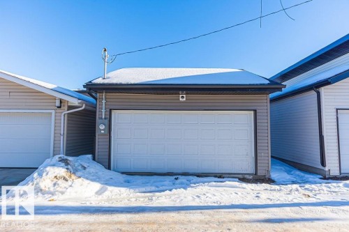 Detached garage with horizontal siding, a paneled overhead door, and a dark fascia - 9814 155 Street, Edmonton, AB - Outdoor