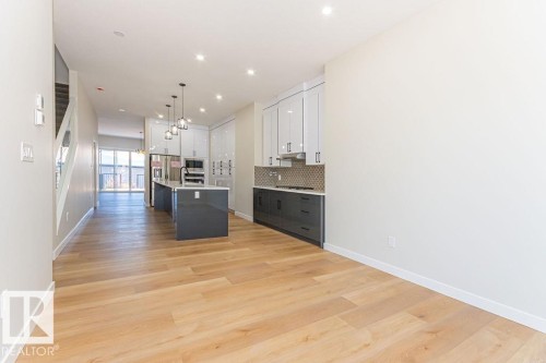 Open-concept living space featuring wood-finish flooring, a modern kitchen with a central island, stainless steel appliances, and recessed lighting throughout - 9814 155 Street, Edmonton, AB - Indoor
