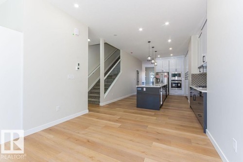 Open-concept living space featuring wood-finish flooring, recessed lighting, and a contemporary kitchen - 9814 155 Street, Edmonton, AB - Indoor Photo Showing Kitchen