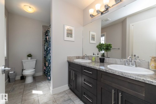 Double vanity with undermount sinks, stone-finish countertop, and dark wood cabinetry - 2016 Redtail Common, Edmonton, AB - Indoor Photo Showing Bathroom
