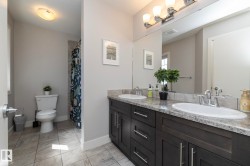 Double vanity with undermount sinks, stone-finish countertop, and dark wood cabinetry - 