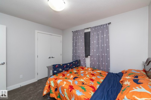 Neutral-toned room featuring a window with blinds, carpeted flooring, and a flush-mount ceiling light fixture - 2016 Redtail Common, Edmonton, AB - Indoor Photo Showing Bedroom