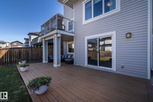 Expansive wood-finish deck with a covered patio area and upper-level balcony - 2016 Redtail Common, Edmonton, AB - Outdoor With Exterior