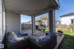 Covered patio featuring wood-finish decking, string lighting, and direct access to a fenced backyard - 