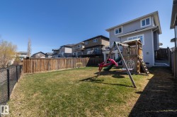 Expansive backyard featuring a lush lawn, privacy fencing, and a chain link fence along one border - 