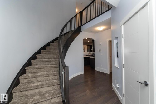 Curved staircase with dark wood-finish handrail and carpeted treads - 2016 Redtail Common, Edmonton, AB - Indoor Photo Showing Other Room
