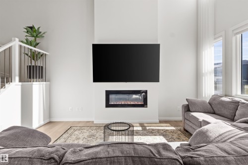 Living space featuring a white vertical fireplace surround, integrated electric fireplace, and wood-finish flooring - 1471 Plum Circle Circle, Edmonton, AB - Indoor Photo Showing Living Room With Fireplace