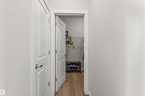 Hallway featuring light wood-finish flooring, white trim, and a white panel door with brushed nickel hardware - 1471 Plum Circle Circle, Edmonton, AB - Indoor Photo Showing Other Room
