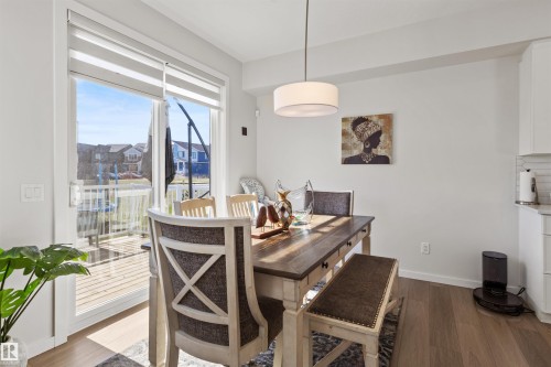 Dining area featuring wood-finish flooring, a contemporary drum pendant light, and a sliding glass door leading to an outdoor deck - 1471 Plum Circle Circle, Edmonton, AB - Indoor Photo Showing Dining Room