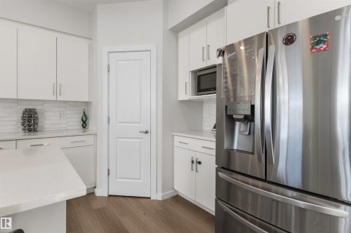 Modern kitchen featuring white cabinetry, light-toned countertops, and a full-size stainless steel refrigerator with an ice and water dispenser - 1471 Plum Circle Circle, Edmonton, AB - Indoor Photo Showing Kitchen