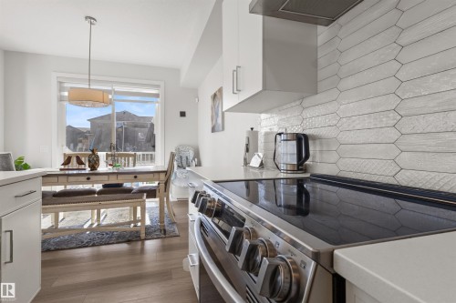 Modern kitchen featuring an electric range, white cabinetry, and a distinct tiled backsplash - 1471 Plum Circle Circle, Edmonton, AB - Indoor Photo Showing Kitchen With Upgraded Kitchen