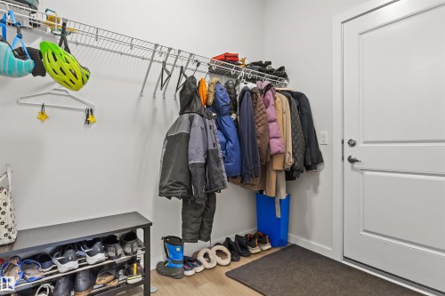 Entryway featuring a white paneled door with brushed nickel hardware, wire shelving, a black storage bench, and wood-finish flooring - 1471 Plum Circle Circle, Edmonton, AB - Indoor With Storage