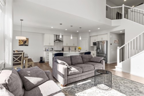 Open-concept living area featuring light wood-finish flooring, white walls, and a two-story ceiling - 1471 Plum Circle Circle, Edmonton, AB - Indoor Photo Showing Living Room