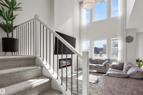 Interior staircase featuring carpeted treads and risers, white newel posts, and black metal balusters - 1471 Plum Circle Circle, Edmonton, AB - Indoor