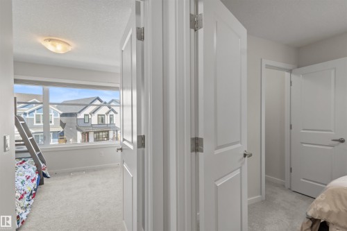 Interior hallway featuring white panel doors with brushed nickel hardware, light gray wall paint, and soft gray carpeting - 1471 Plum Circle Circle, Edmonton, AB - Indoor Photo Showing Other Room