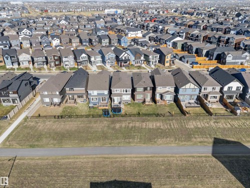 Modern residential development featuring a variety of architectural styles, paved streets, and a pedestrian pathway bordering green space - 1471 Plum Circle Circle, Edmonton, AB - Outdoor With View
