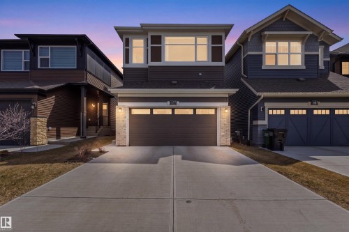 Contemporary brown siding residence featuring an integrated garage, stone pillar accents, and a concrete driveway - 1471 Plum Circle Circle, Edmonton, AB - Outdoor With Facade