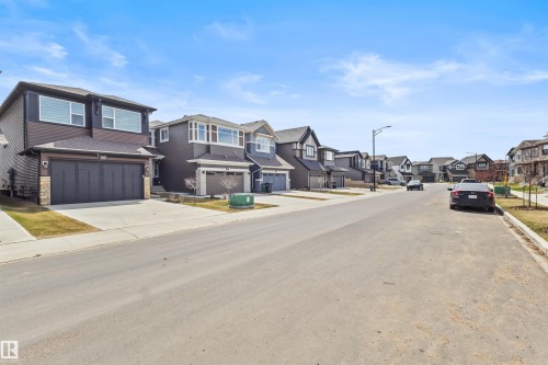 Contemporary residences featuring dark siding, stone accents, attached garages, and concrete driveways - 1471 Plum Circle Circle, Edmonton, AB - Outdoor With Facade