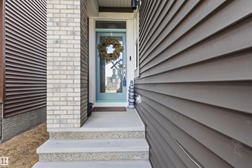 Entryway featuring a light blue front door, concrete steps, and a complementary brick facade - 1471 Plum Circle Circle, Edmonton, AB - Outdoor