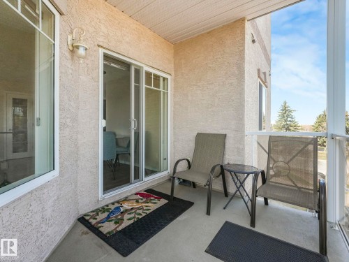 Private balcony with textured stucco exterior, white framed windows, and a sliding glass door - 317 2420 108 Street, Edmonton, AB - Outdoor With Deck Patio Veranda With Exterior