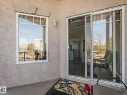 Exterior patio featuring a textured stucco finish, white frame windows with upper divided lites, and a sliding glass door with a screen - 