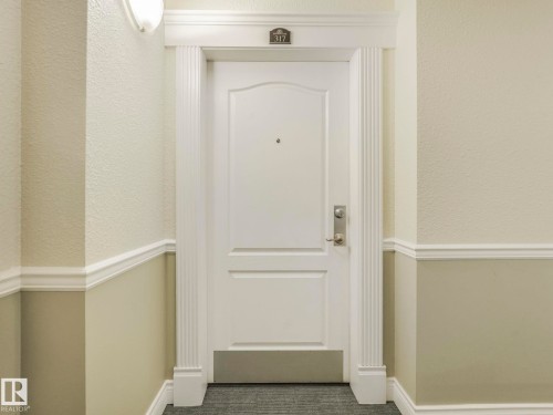White paneled entry door with fluted trim, crown molding, and brushed nickel hardware - 317 2420 108 Street, Edmonton, AB - Indoor Photo Showing Other Room