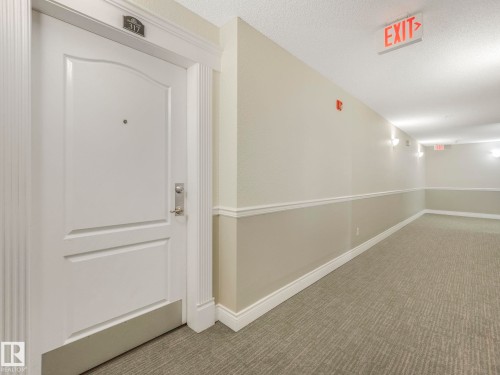 Entry door with decorative molding and brushed nickel hardware - 317 2420 108 Street, Edmonton, AB - Indoor Photo Showing Other Room