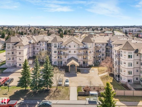 Multi-story residential building featuring light-colored stucco siding, dark shingle roofing, and multiple private balconies with decorative railings - 317 2420 108 Street, Edmonton, AB - Outdoor With Facade