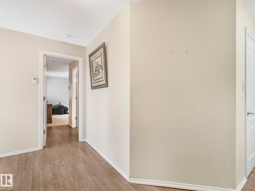 Interior hallway featuring wood-finish flooring, light neutral wall paint, and white trim molding - 317 2420 108 Street, Edmonton, AB - Indoor Photo Showing Other Room