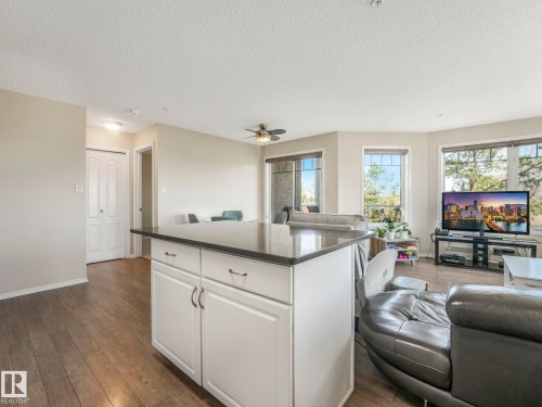 Kitchen island with white cabinetry and a dark countertop - 317 2420 108 Street, Edmonton, AB - Indoor Photo Showing Living Room