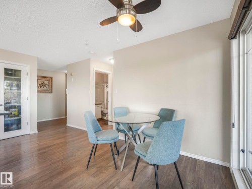 Dining area with wood-finish flooring, a ceiling fan with integrated lighting, and a glass-paneled door - 317 2420 108 Street, Edmonton, AB - Indoor Photo Showing Dining Room