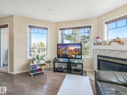 Living area featuring wood-finish flooring, a fireplace with a tiled surround and mantel, and multiple windows with blinds - 