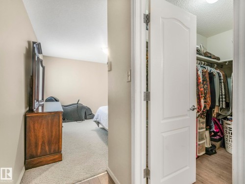 Interior hallway featuring a white paneled door, light neutral wall paint, and textured ceiling - 317 2420 108 Street, Edmonton, AB - Indoor
