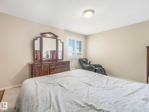 Well-lit room featuring neutral wall paint, a white textured ceiling, a flush-mount ceiling light fixture, and a window with white plantation shutters - 317 2420 108 Street, Edmonton, AB - Indoor Photo Showing Bedroom