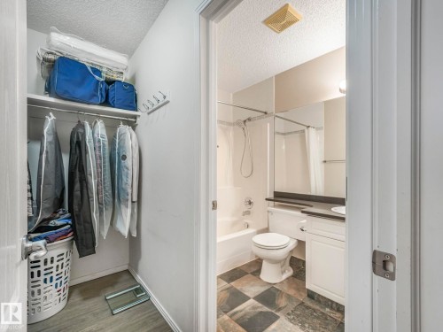 Built-in closet shelving and hanging rod with wood-finish flooring - 317 2420 108 Street, Edmonton, AB - Indoor Photo Showing Bathroom