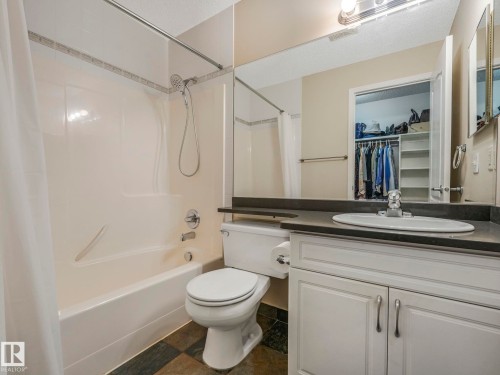 Bathroom featuring a white vanity with cabinet storage, an integrated sink, and a dark countertop - 317 2420 108 Street, Edmonton, AB - Indoor Photo Showing Bathroom