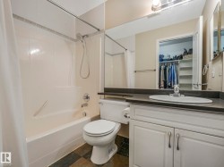 Bathroom featuring a white vanity with cabinet storage, an integrated sink, and a dark countertop - 