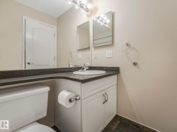 Bathroom vanity with an integrated sink, dark countertop, and white cabinetry - 
