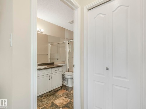Bathroom vanity with a round basin sink, dark countertop, and white cabinetry - 317 2420 108 Street, Edmonton, AB - Indoor