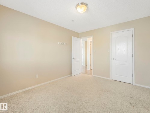 Neutral-toned walls and plush carpeting provide a versatile foundation for personalization - 317 2420 108 Street, Edmonton, AB - Indoor Photo Showing Other Room