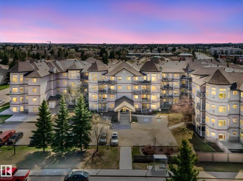 Multi-story residential building with light-toned exterior and dark gabled roofs, featuring multiple private balconies with decorative railings - 317 2420 108 Street, Edmonton, AB - Outdoor