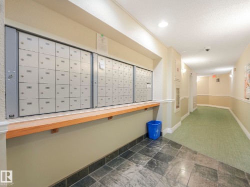 Secure mailboxes integrated into a hallway featuring stone tile flooring and a light wood-finish shelf - 317 2420 108 Street, Edmonton, AB - Indoor Photo Showing Other Room