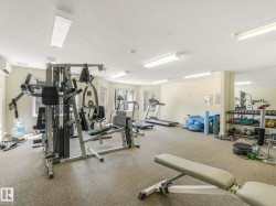 Dedicated fitness room featuring cushioned flooring, multiple windows, and bright overhead lighting - 